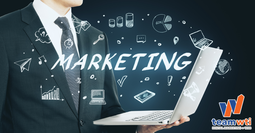 A man in a suit holding a laptop with the word "Marketing" in large letters